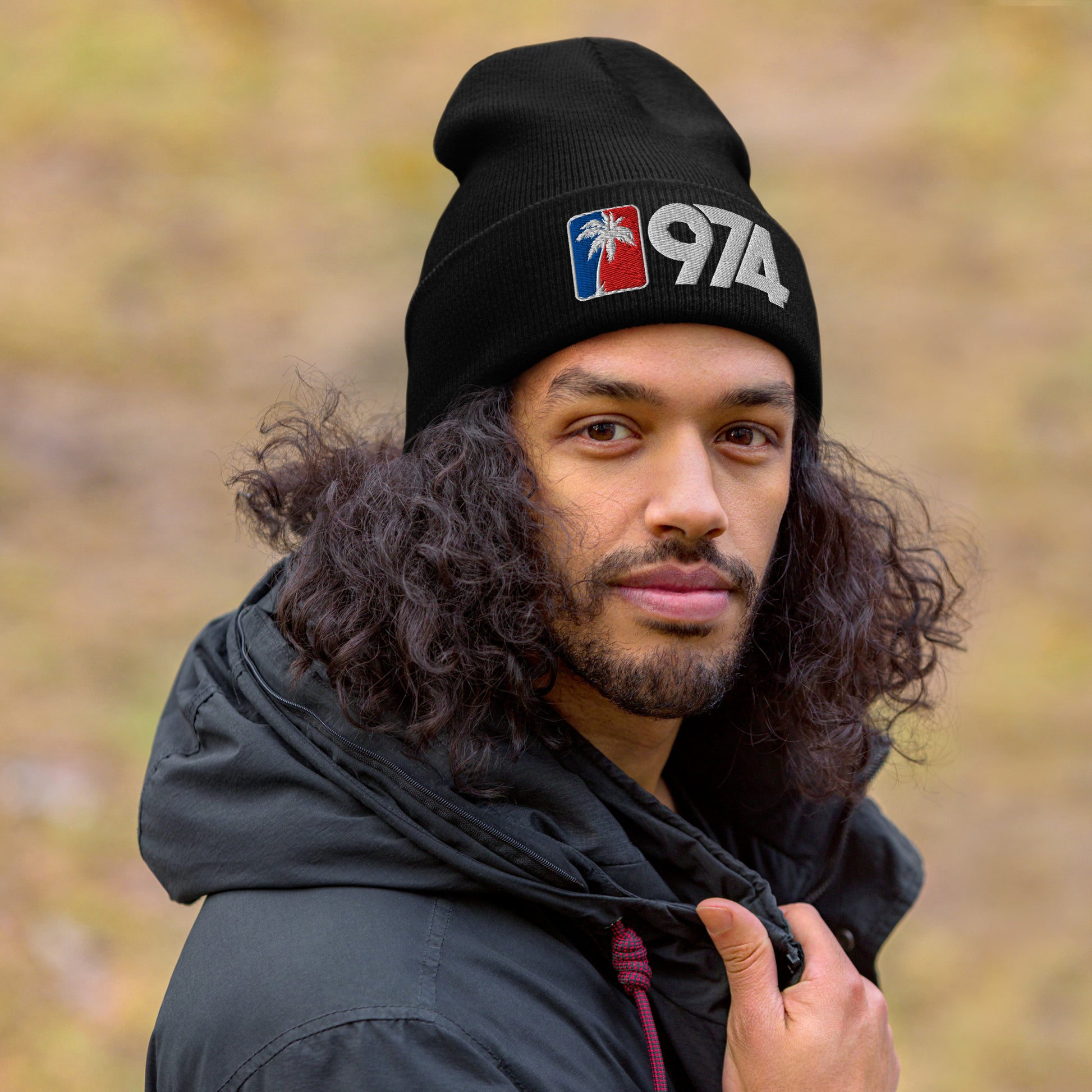 Homme portant un bonnet 974 Ile de la Réunion avec palmier blanc sur fond rouge et bleu, design streetwear péï.